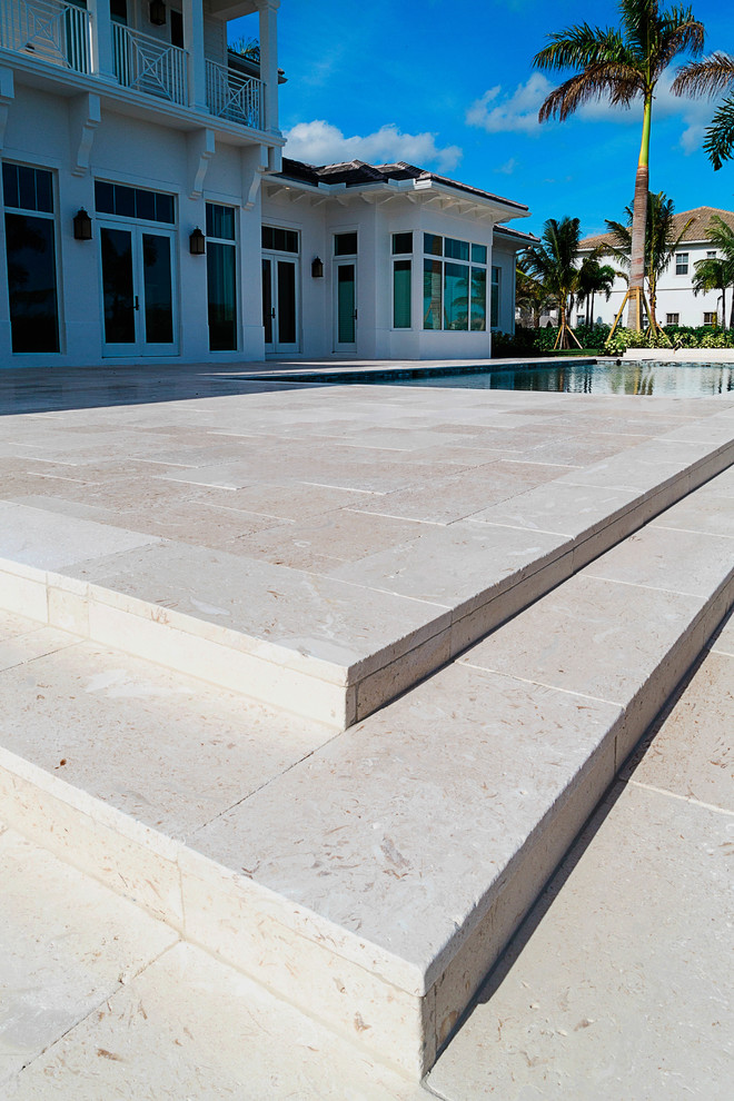 This is an example of a mid-sized tropical backyard patio in Miami with natural stone pavers and a gazebo/cabana.