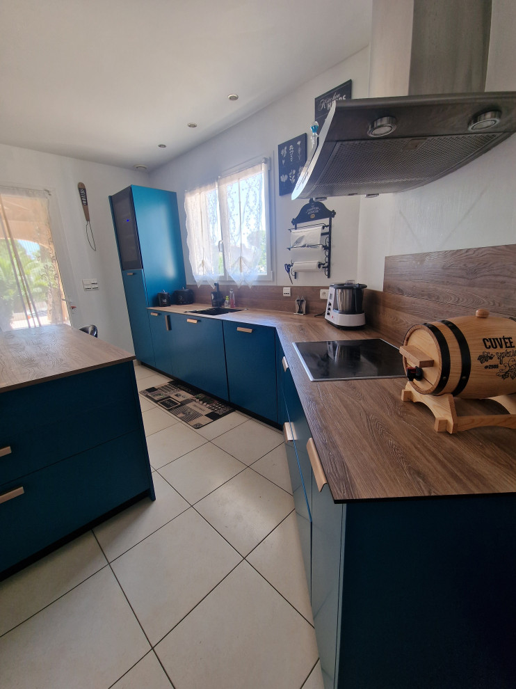 Design ideas for a large industrial galley separate kitchen in Toulouse with an undermount sink, beaded inset cabinets, blue cabinets, wood benchtops, brown splashback, timber splashback, panelled appliances, ceramic floors, with island, beige floor and brown benchtop.