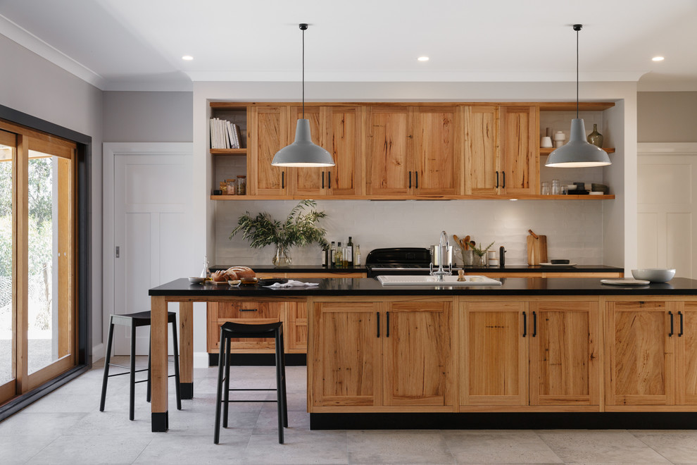 Photo of a country galley kitchen in Adelaide with a drop-in sink, shaker cabinets, medium wood cabinets, white splashback, with island and grey floor.