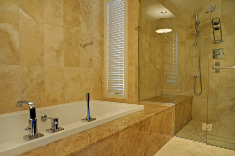 This is an example of a contemporary bathroom in Calgary with a drop-in tub, an alcove shower, beige tile and stone tile.