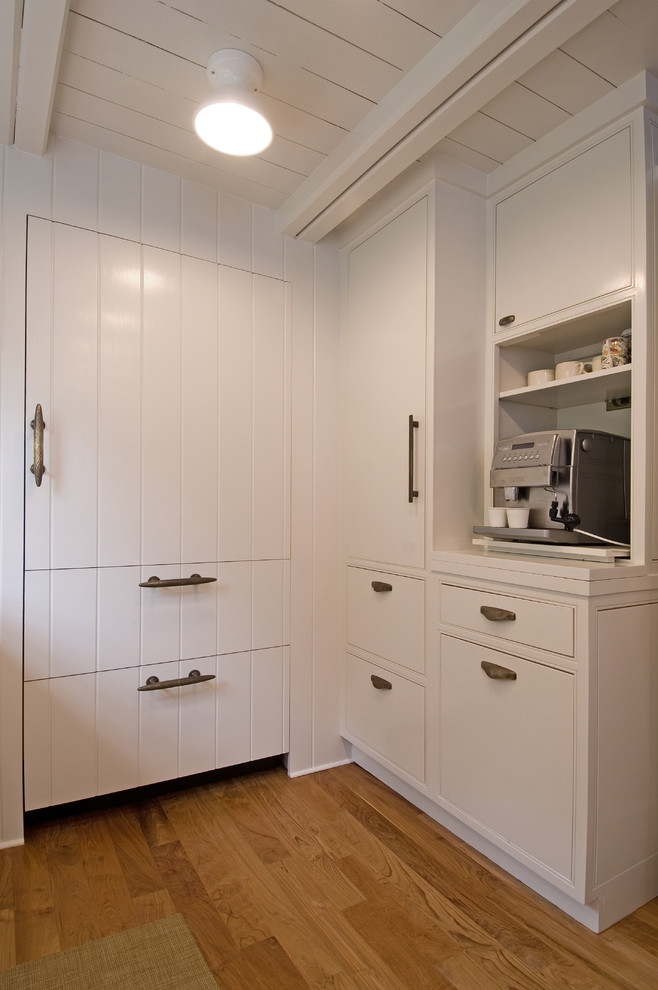 Photo of a traditional kitchen in New York with flat-panel cabinets, white cabinets and panelled appliances.