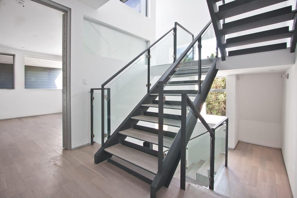 This is an example of a mid-sized modern wood u-shaped staircase in Los Angeles with wood risers and glass railing.