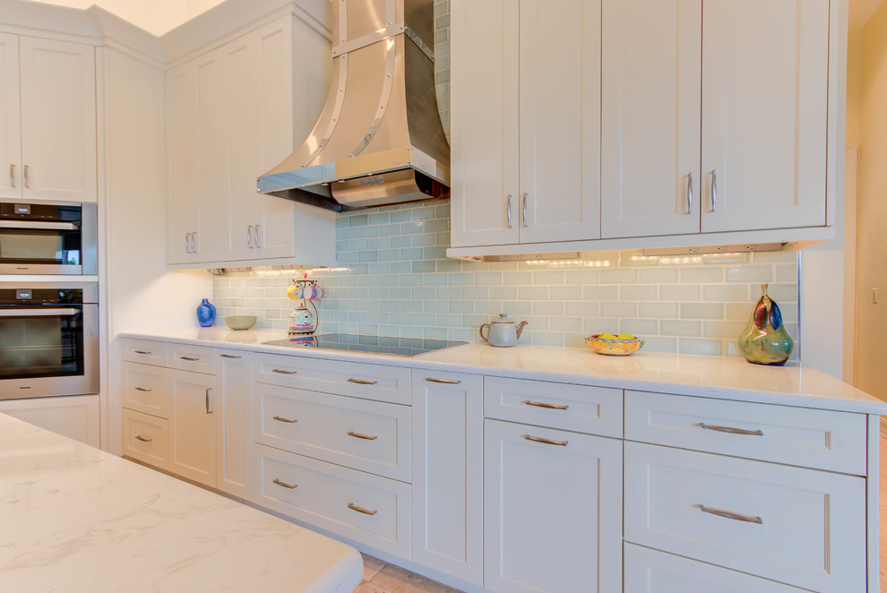 Example of a large transitional single-wall enclosed kitchen design with an undermount sink, flat-panel cabinets, white cabinets, quartz countertops, blue backsplash, stone tile backsplash, stainless steel appliances and an island