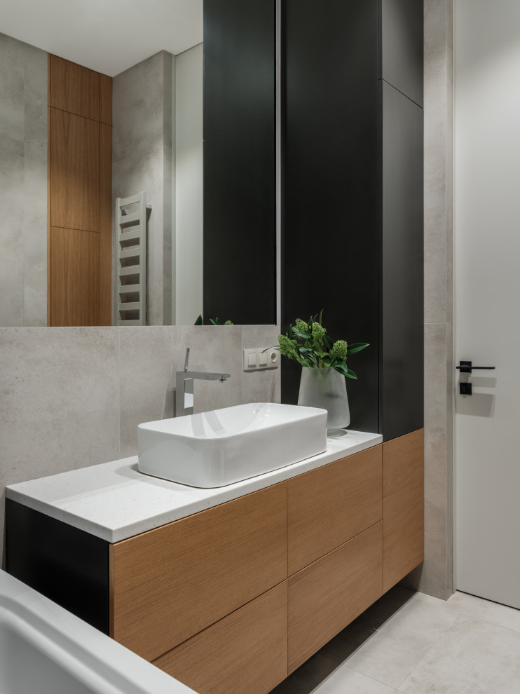 Photo of a mid-sized contemporary master bathroom in Saint Petersburg with flat-panel cabinets, medium wood cabinets, an undermount tub, a wall-mount toilet, black tile, ceramic tile, beige walls, porcelain floors, a drop-in sink, solid surface benchtops, beige floor, a shower curtain, beige benchtops, a single vanity and a floating vanity.
