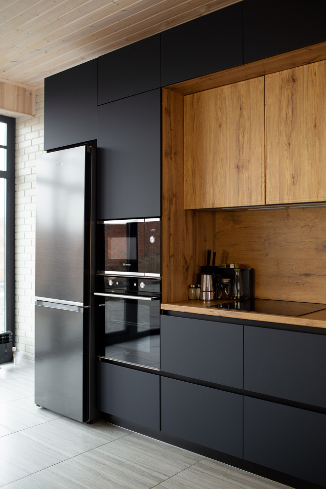 This is an example of a large industrial grey and white single-wall kitchen/diner in Other with a submerged sink, flat-panel cabinets, black cabinets, laminate countertops, brown splashback, all types of splashback, black appliances, laminate floors, an island, beige floors, brown worktops and a timber clad ceiling.