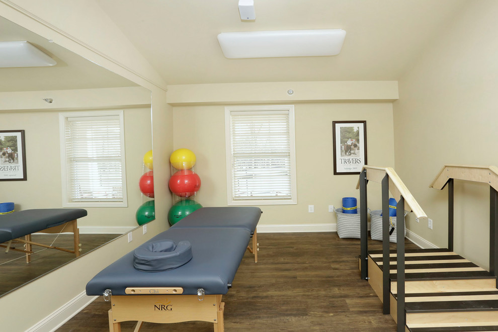 Photo of a mid-sized traditional home gym in Other with beige walls and brown floor.
