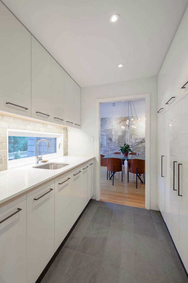 Contemporary galley kitchen in Boston with an undermount sink, flat-panel cabinets, white cabinets, grey splashback, concrete benchtops, white appliances, black floor, yellow benchtop and slate floors.