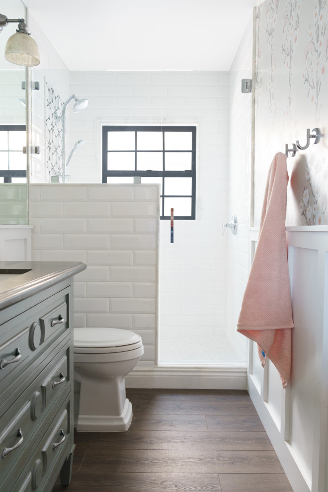 Cette image montre une salle de bain grise et rose de taille moyenne pour enfant avec un placard en trompe-l'oeil, des portes de placard bleues, une douche ouverte, WC séparés, un carrelage blanc, un carrelage métro, un mur blanc, un sol en vinyl, un lavabo encastré, un plan de toilette en quartz modifié, un sol marron, une cabine de douche à porte battante, un plan de toilette gris, meuble simple vasque, meuble-lavabo sur pied et du papier peint.