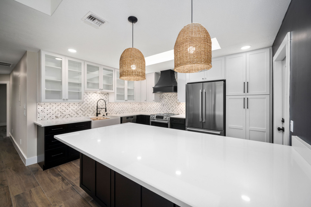 Inspiration for a mid-sized modern l-shaped eat-in kitchen in Atlanta with a farmhouse sink, shaker cabinets, black cabinets, granite benchtops, white splashback, granite splashback, stainless steel appliances, painted wood floors, with island and brown floor.