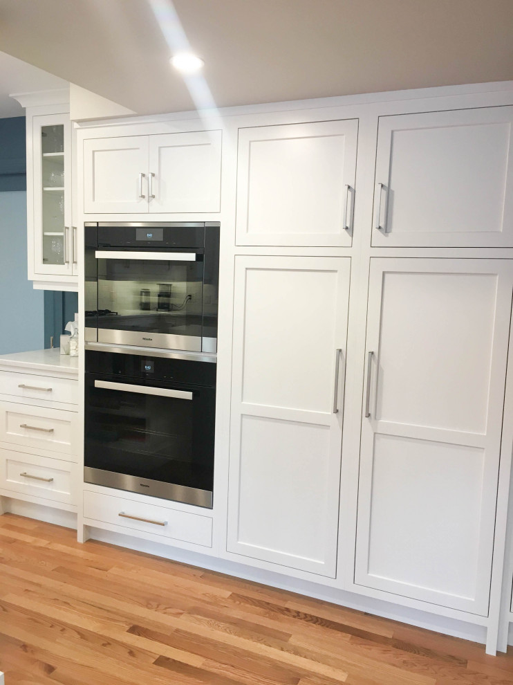 Inspiration for a large transitional u-shaped light wood floor and beige floor eat-in kitchen remodel with a double-bowl sink, shaker cabinets, white cabinets, quartzite countertops, white backsplash, subway tile backsplash, stainless steel appliances, an island and white countertops