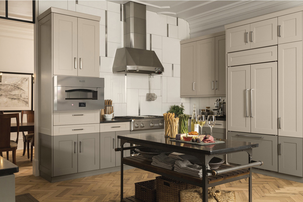 Inspiration for a mid-sized transitional l-shaped medium tone wood floor and brown floor open concept kitchen remodel with stainless steel appliances, an undermount sink, shaker cabinets, white cabinets, granite countertops, white backsplash, porcelain backsplash and an island