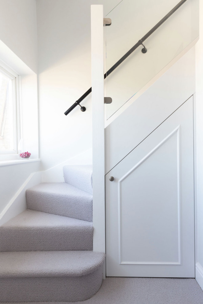 Imagen de escalera en L moderna de tamaño medio con escalones enmoquetados, contrahuellas enmoquetadas y barandilla de metal