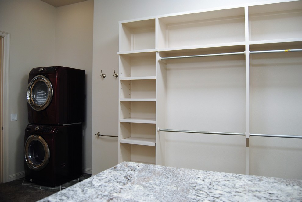 This is an example of a large traditional utility room in Austin with open cabinets, white cabinets, white walls and a stacked washer and dryer.