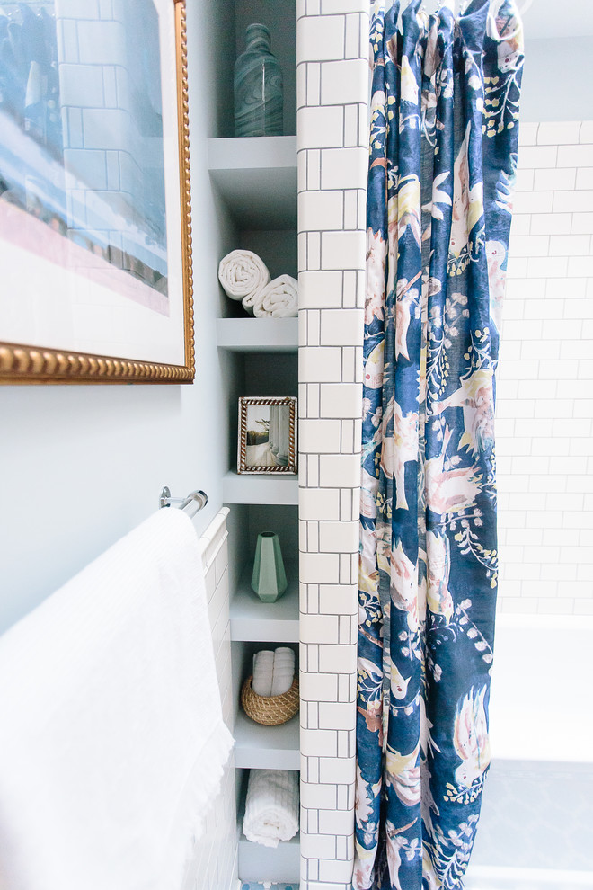 Photo of a mid-sized eclectic 3/4 bathroom in DC Metro with shaker cabinets, white cabinets, an alcove tub, a shower/bathtub combo, a two-piece toilet, white tile, ceramic tile, blue walls, ceramic floors, a drop-in sink, marble benchtops, blue floor, a shower curtain and grey benchtops.