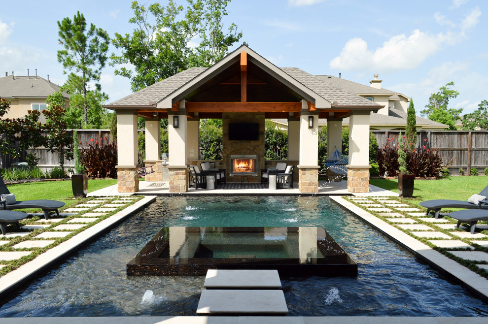 Photo of a large traditional backyard custom-shaped pool in Houston with a hot tub and natural stone pavers.