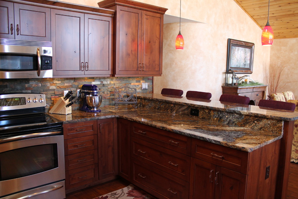 This is an example of a mid-sized mediterranean u-shaped open plan kitchen in Denver with an undermount sink, recessed-panel cabinets, granite benchtops, multi-coloured splashback, stone tile splashback, stainless steel appliances, medium hardwood floors, medium wood cabinets, a peninsula and brown floor.