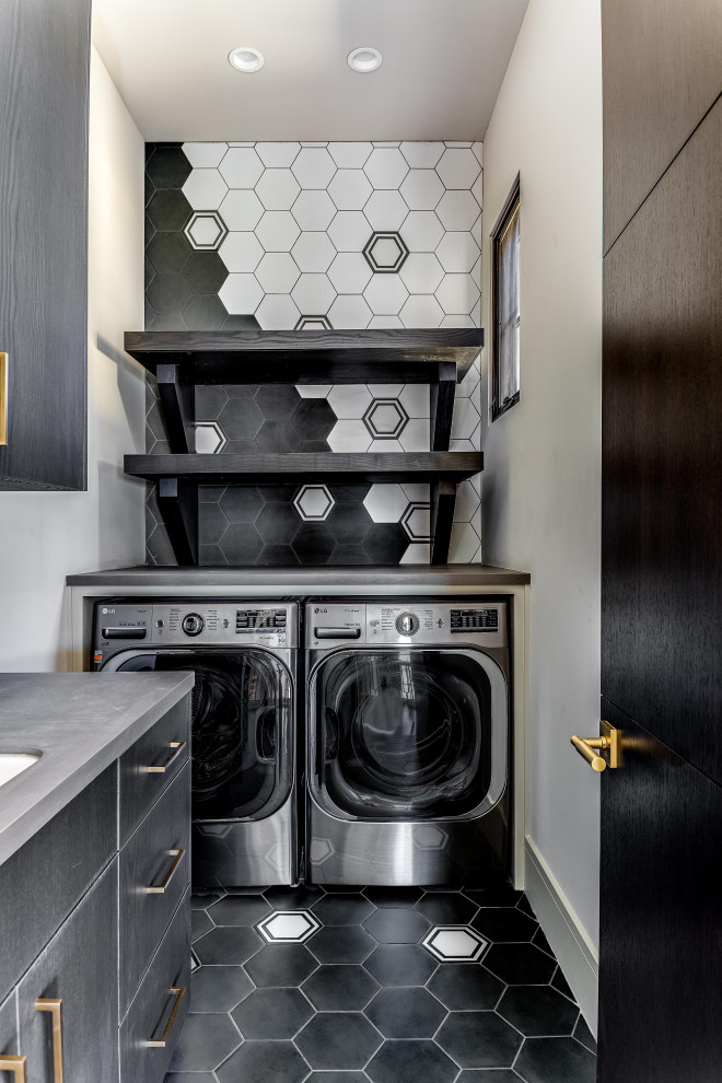 Exempel på en mellanstor modern grå linjär grått tvättstuga enbart för tvätt, med en tvättmaskin och torktumlare bredvid varandra, en nedsänkt diskho, släta luckor, grå skåp, bänkskiva i kvarts, beige väggar, klinkergolv i porslin och svart golv