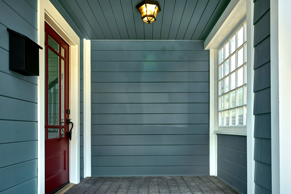 Amerikansk inredning av en stor ingång och ytterdörr, med blå väggar, mellanmörkt trägolv, en röd dörr och brunt golv