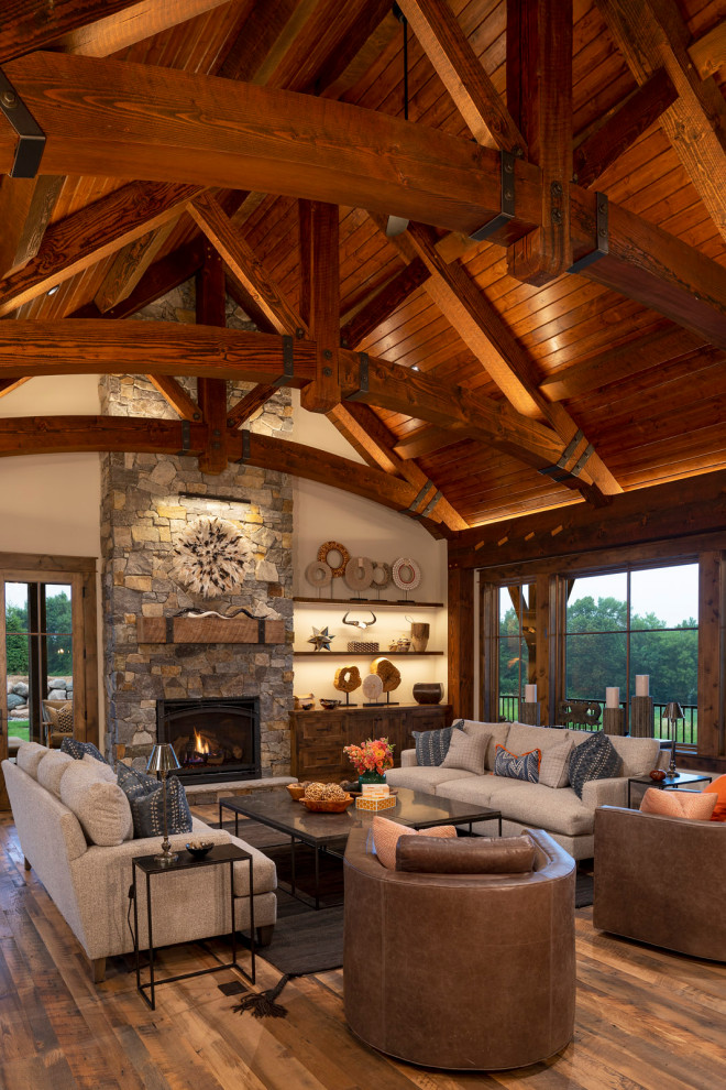 Design ideas for an expansive country open concept family room in Minneapolis with grey walls, medium hardwood floors, a standard fireplace, no tv, multi-coloured floor, exposed beam and planked wall panelling.