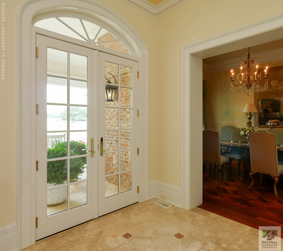 Foto de puerta principal abovedada grande con paredes amarillas, suelo de baldosas de cerámica, puerta doble, puerta blanca y suelo beige