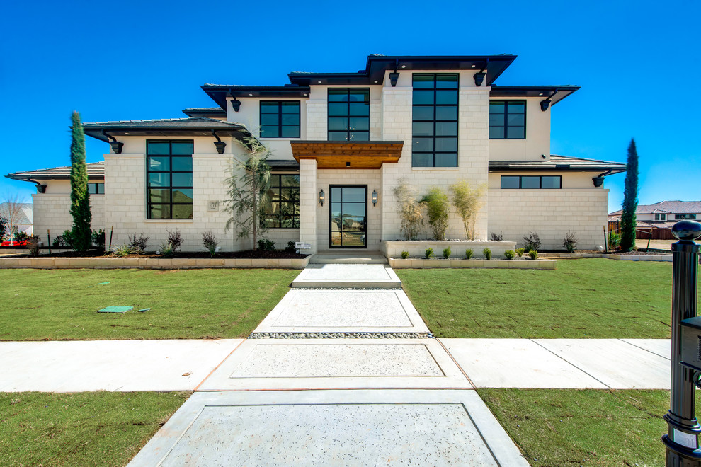 Photo of a large contemporary two-storey white exterior in Dallas with stone veneer.