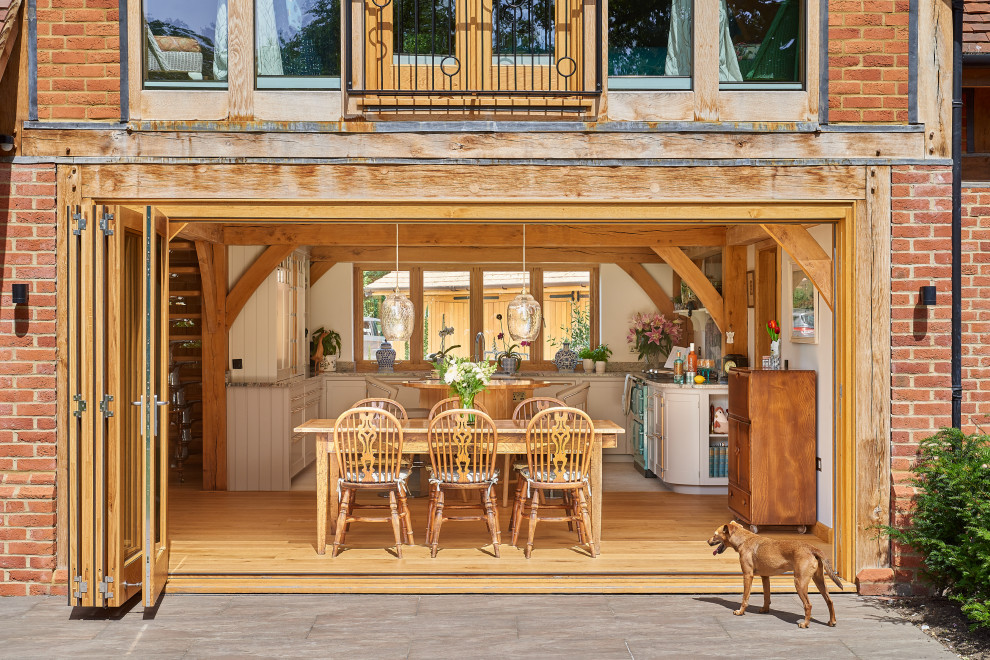 Immagine di una sala da pranzo aperta verso la cucina country con pavimento in legno massello medio e pavimento marrone
