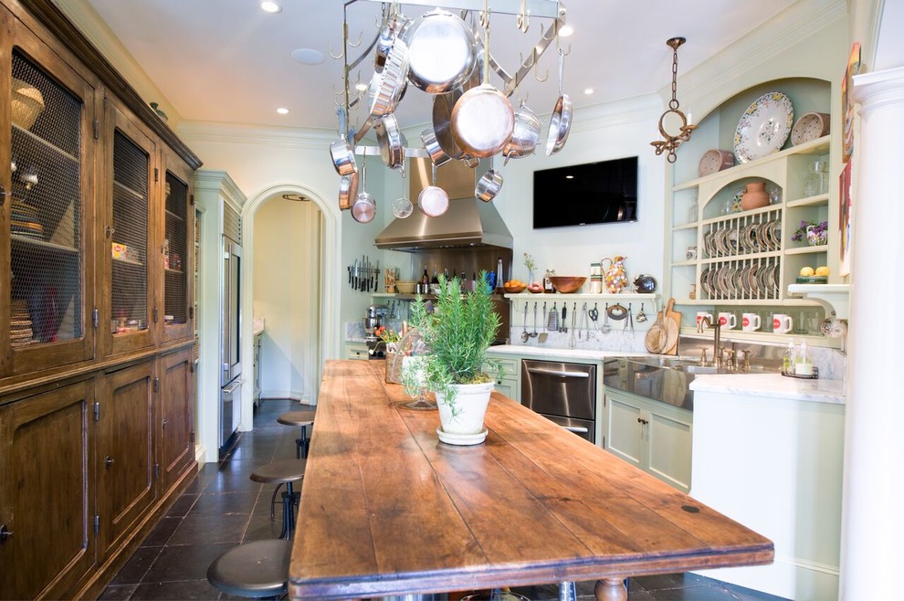 Photo of a mid-sized eclectic single-wall eat-in kitchen in Houston with a farmhouse sink, shaker cabinets, marble benchtops, stainless steel appliances, with island and brown floor.