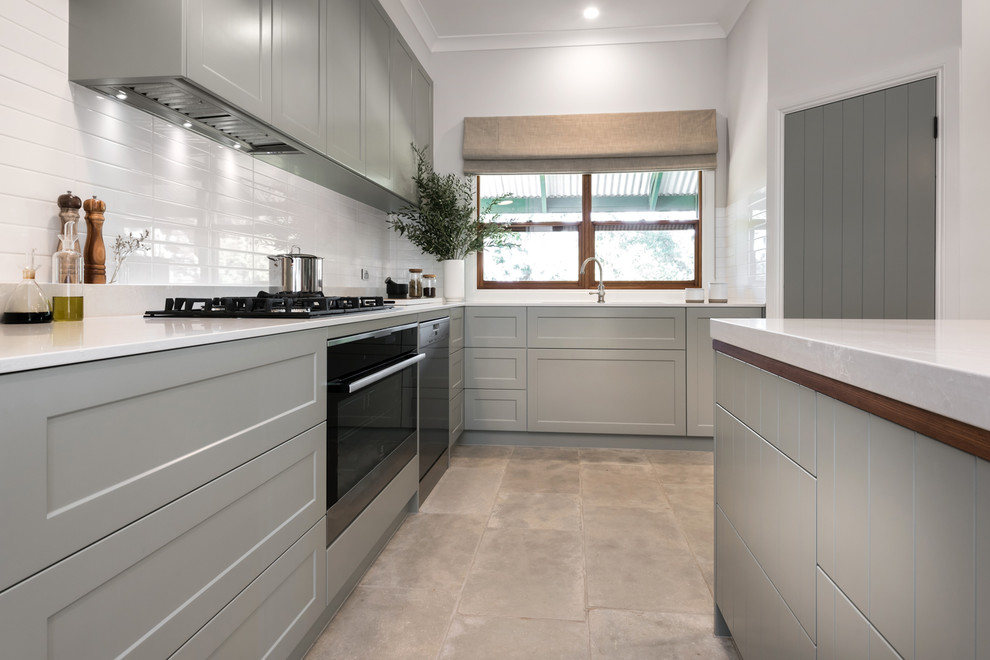 This is an example of a large contemporary l-shaped open plan kitchen in Adelaide with grey cabinets, white splashback, subway tile splashback, stainless steel appliances, terra-cotta floors, with island, white benchtop, quartz benchtops, grey floor, an undermount sink and shaker cabinets.