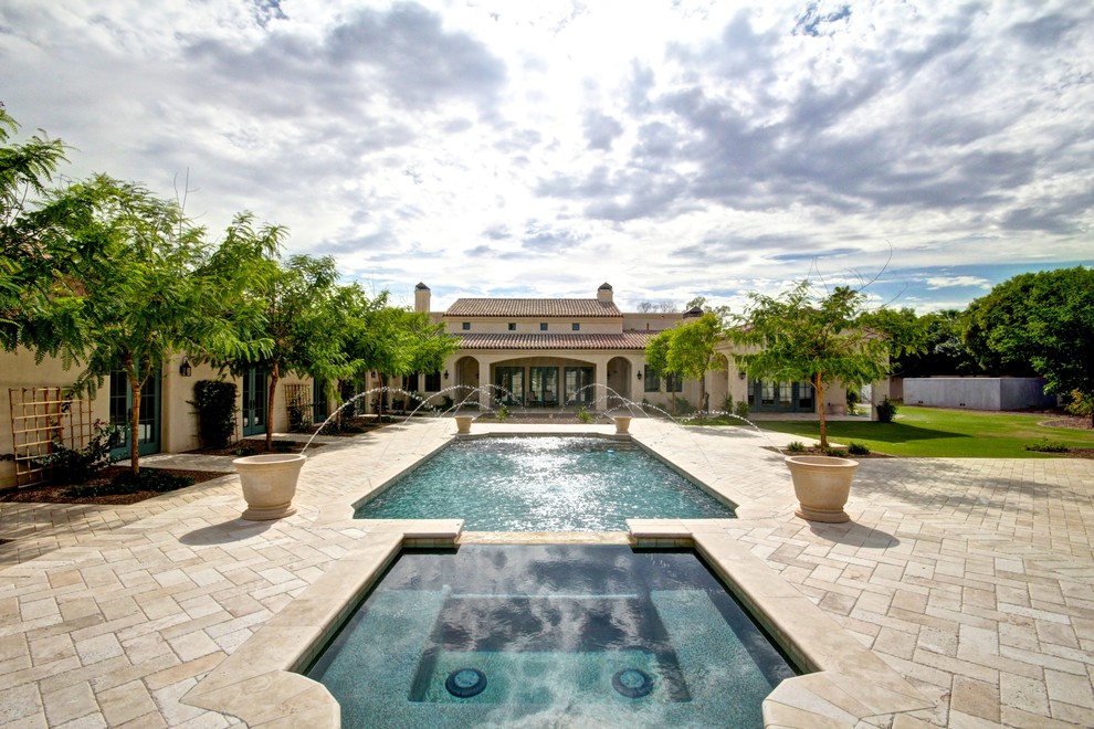 Inspiration for a large mediterranean backyard rectangular lap pool in Phoenix with a water feature and tile.