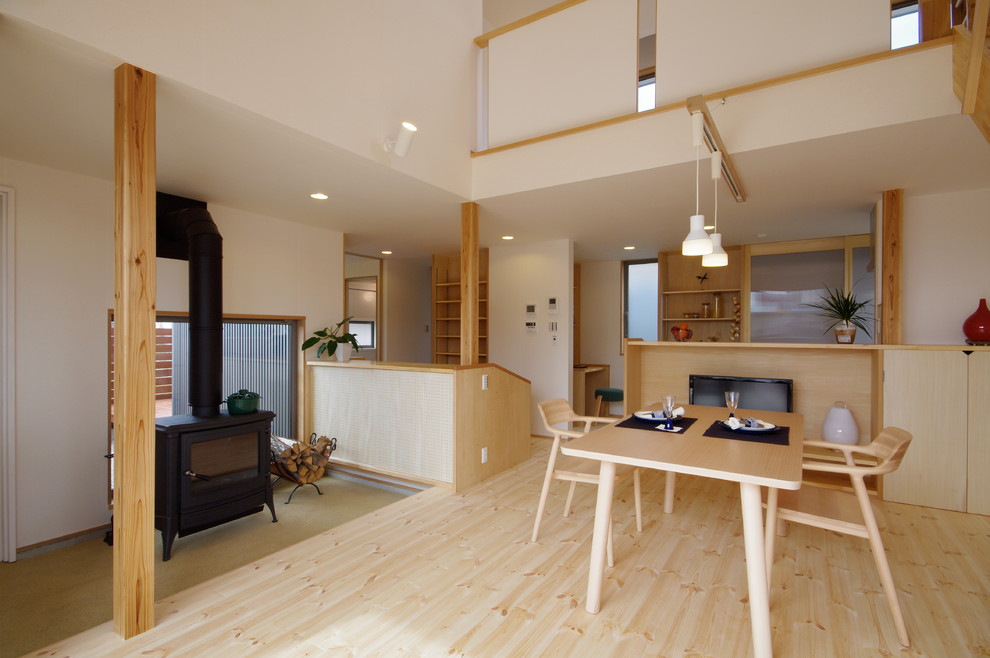 Photo of a mid-sized scandinavian open concept living room in Tokyo with white walls, light hardwood floors, a standard fireplace, a freestanding tv, a wood fireplace surround and beige floor.