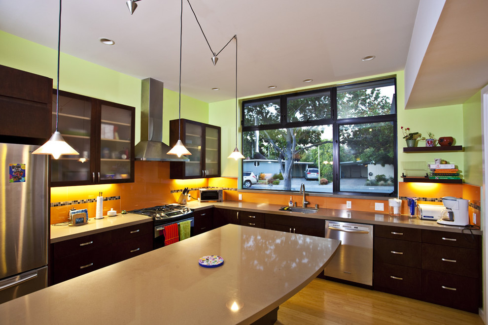 Inspiration for a mid-sized contemporary l-shaped eat-in kitchen in San Francisco with stainless steel appliances, glass-front cabinets, dark wood cabinets, orange splashback, a single-bowl sink, quartz benchtops, glass tile splashback, light hardwood floors, with island and beige floor.