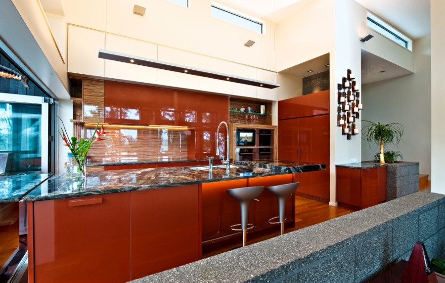 Inspiration for a large modern l-shaped eat-in kitchen in Auckland with multi-coloured splashback, glass sheet splashback, black appliances, with island, an undermount sink, flat-panel cabinets, red cabinets, granite benchtops and light hardwood floors.