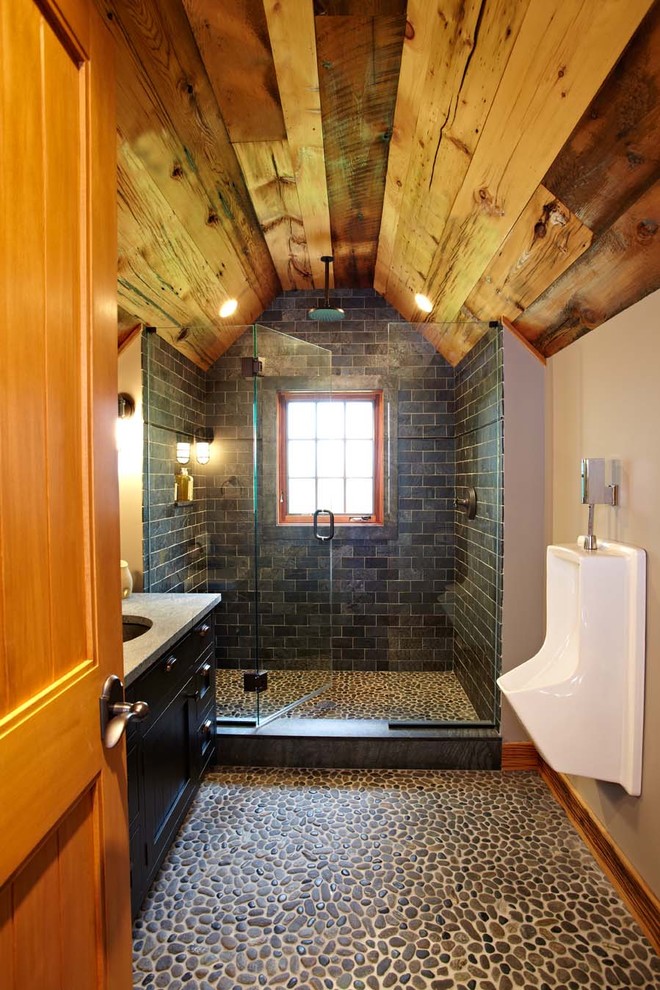 This is an example of a traditional bathroom in New York with an urinal, pebble tile floors and slate.
