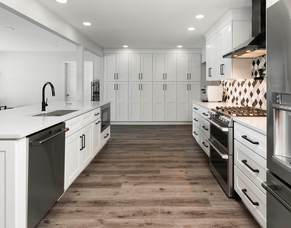 Example of a large transitional vinyl floor and brown floor kitchen pantry design in Orlando with an undermount sink, shaker cabinets, white cabinets, quartzite countertops, multicolored backsplash, porcelain backsplash, stainless steel appliances, an island and white countertops