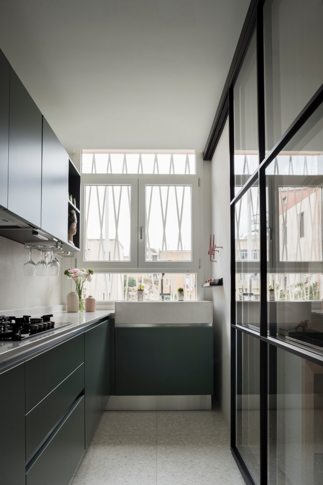 Contemporary l-shaped separate kitchen in Cagliari with a single-bowl sink, flat-panel cabinets, green cabinets, granite benchtops, grey splashback, granite splashback, stainless steel appliances, no island, grey floor and grey benchtop.