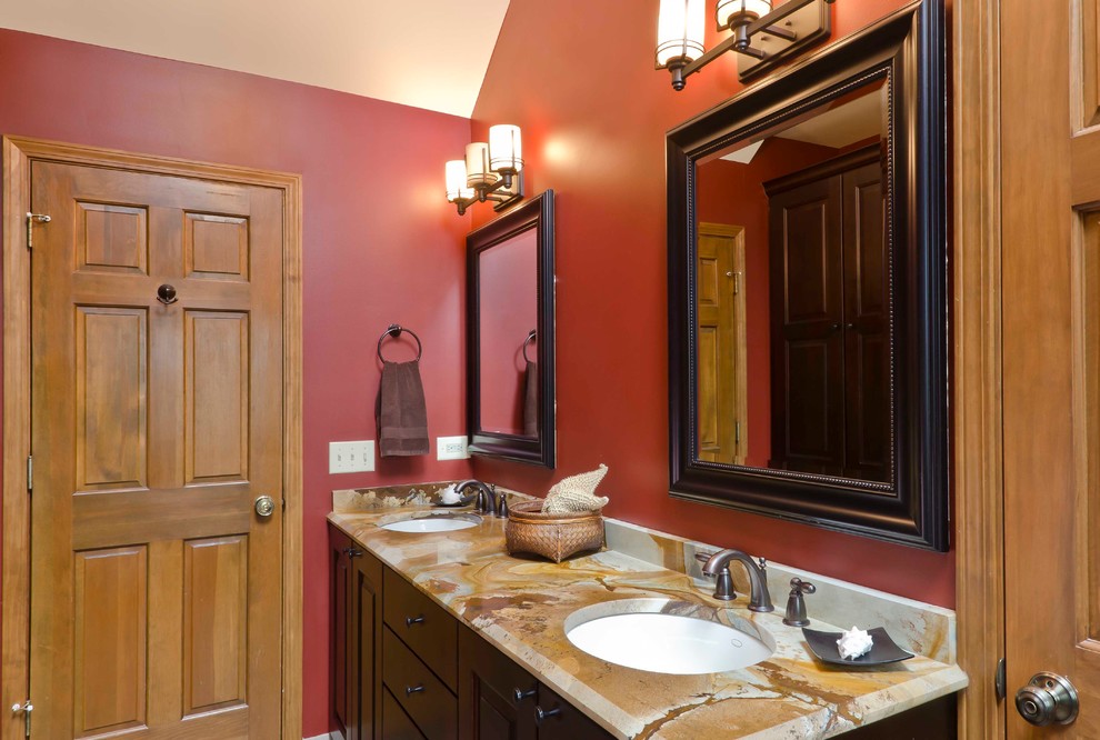 This is an example of a mid-sized traditional kids bathroom in Chicago with an undermount sink, raised-panel cabinets, dark wood cabinets, marble benchtops, an alcove shower, beige tile, porcelain tile, red walls and porcelain floors.