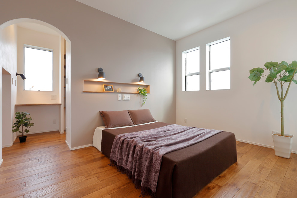 Scandinavian master bedroom in Other with grey walls, medium hardwood floors and brown floor.