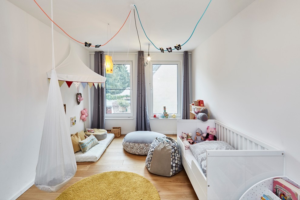 Photo of a mid-sized scandinavian toddler room for girls in Essen with white walls, light hardwood floors and beige floor.