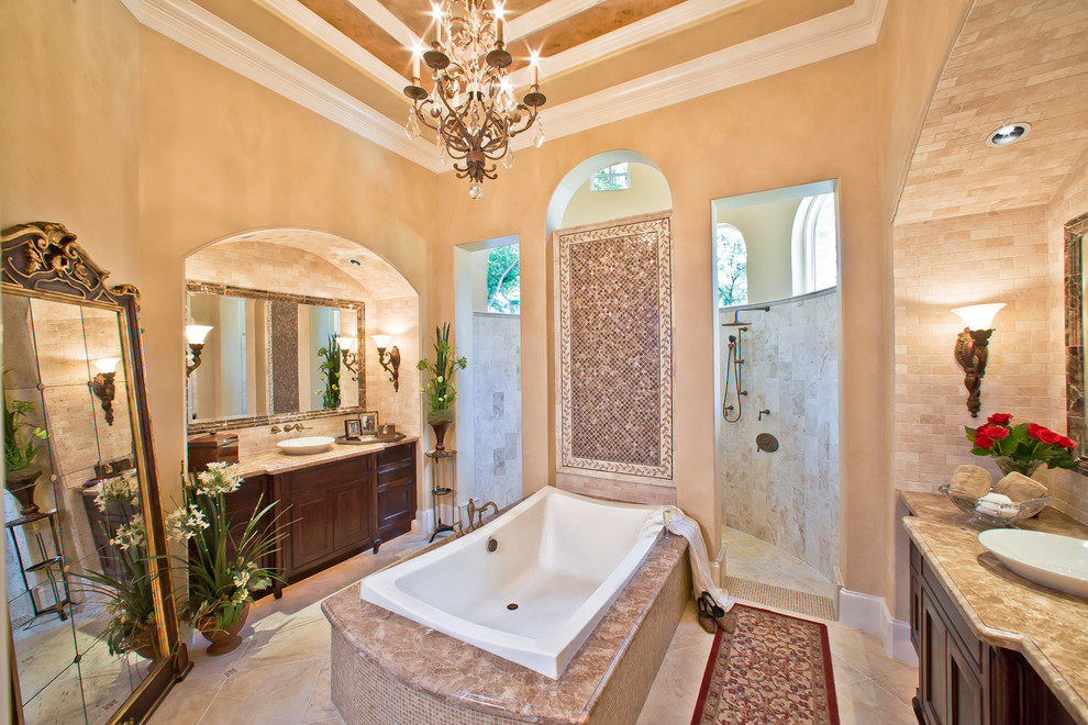 Inspiration for a mediterranean bathroom in Houston with a vessel sink, recessed-panel cabinets, dark wood cabinets, a drop-in tub, an open shower, beige tile and an open shower.