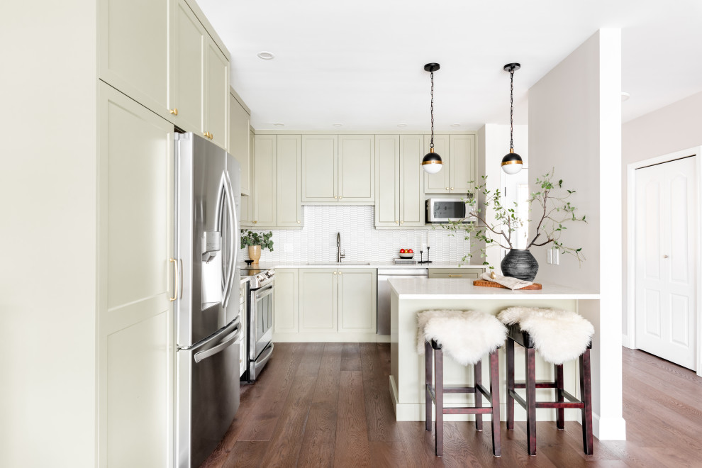 Inspiration for a small transitional brown floor kitchen remodel with shaker cabinets, green cabinets, white backsplash, stainless steel appliances, an island and white countertops