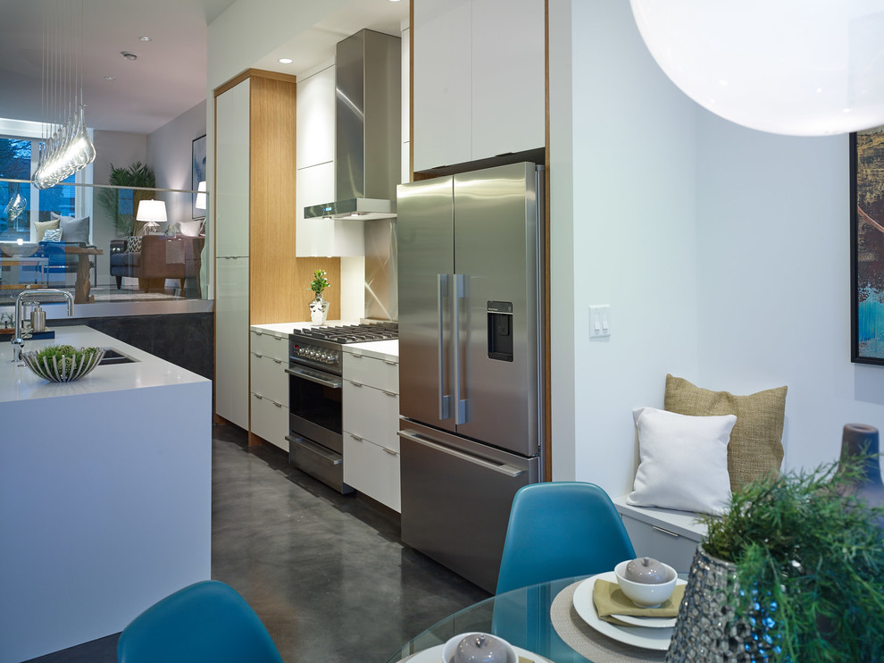 Mid-sized contemporary galley eat-in kitchen in Vancouver with an undermount sink, flat-panel cabinets, white cabinets, quartz benchtops, white splashback, glass sheet splashback, stainless steel appliances, concrete floors and with island.