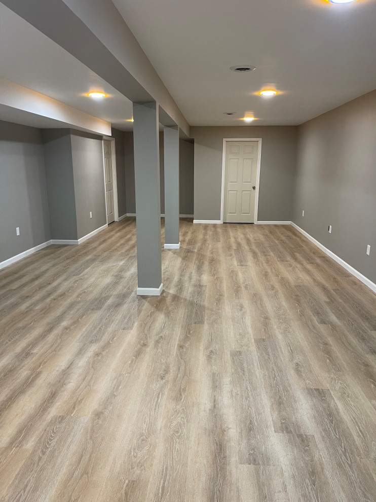 Inspiration for a large modern underground vinyl floor and brown floor basement remodel in Cleveland with gray walls and no fireplace