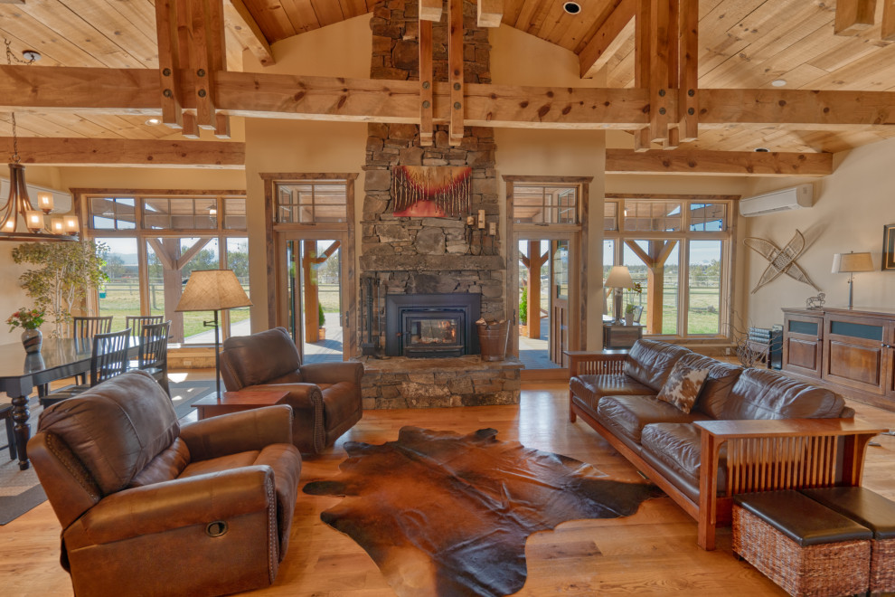 Example of a large country open concept brown floor and exposed beam living room design in Other with beige walls, a standard fireplace and a brick fireplace