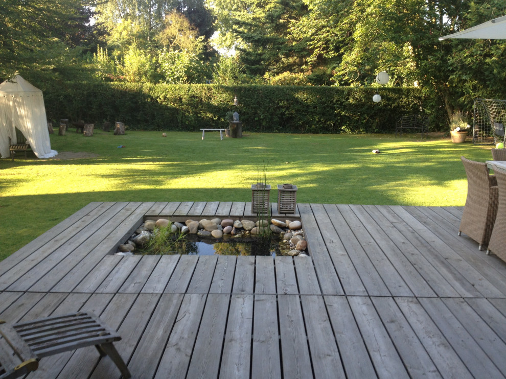 Mittelgroßer Klassischer Garten im Sommer, neben dem Haus mit direkter Sonneneinstrahlung, Dielen und Wasserspiel in Düsseldorf