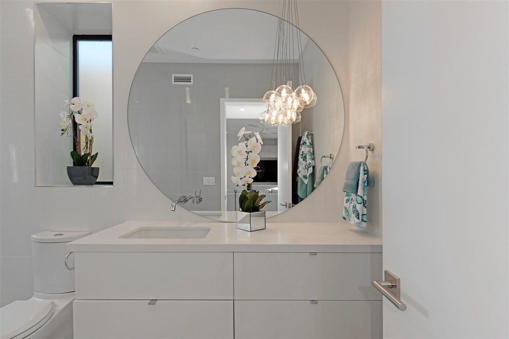 Photo of a mid-sized contemporary kids bathroom in San Diego with flat-panel cabinets, white cabinets, an undermount tub, an open shower, a one-piece toilet, white tile, ceramic tile, white walls, ceramic floors, an undermount sink, engineered quartz benchtops, grey floor and a hinged shower door.