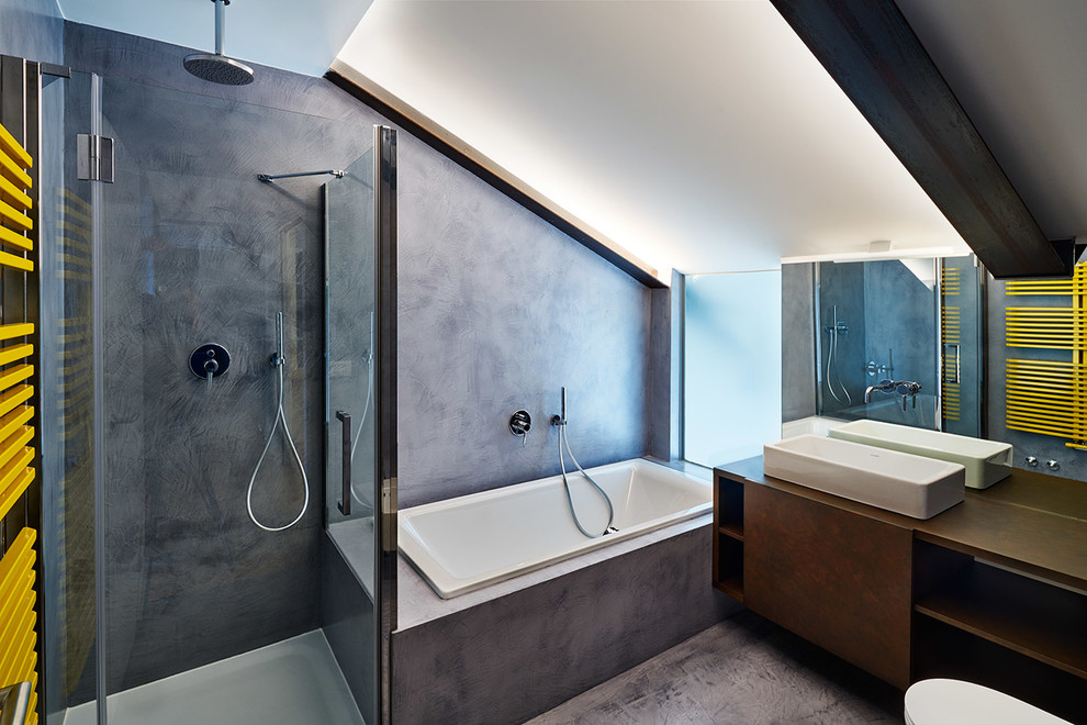 Inspiration for a mid-sized contemporary master wet room bathroom in Milan with flat-panel cabinets, brown cabinets, grey walls, a vessel sink, a drop-in tub, a wall-mount toilet, concrete floors, wood benchtops, grey floor and a hinged shower door.