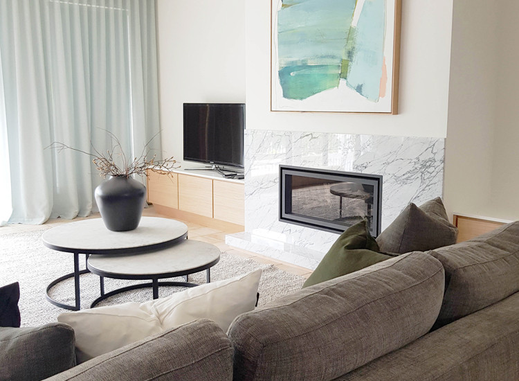 Cette image montre un salon minimaliste avec un mur blanc, tomettes au sol, une cheminée standard et un manteau de cheminée en pierre.