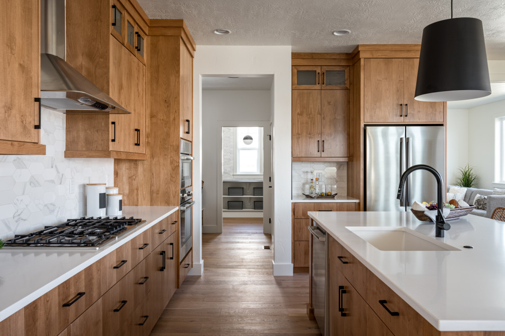 Inredning av ett klassiskt vit vitt l-kök, med en undermonterad diskho, släta luckor, skåp i mellenmörkt trä, vitt stänkskydd, rostfria vitvaror, mellanmörkt trägolv, en köksö och brunt golv