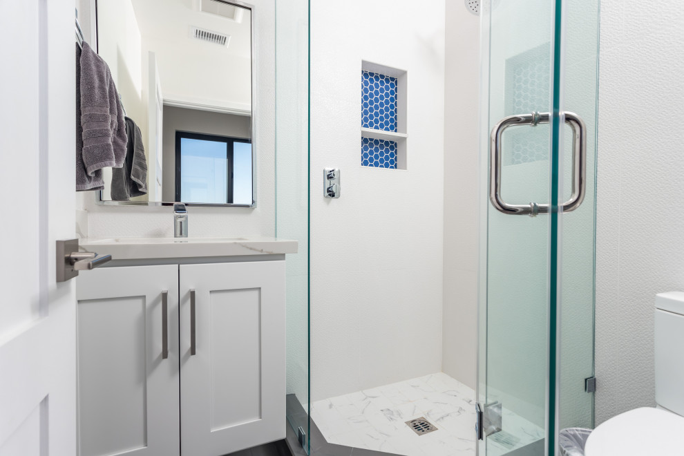 Photo of a modern family bathroom in Los Angeles with shaker cabinets, white cabinets, a hot tub, an alcove shower, a one-piece toilet, white tiles, ceramic tiles, white walls, marble flooring, a submerged sink, quartz worktops, multi-coloured floors, a hinged door, multi-coloured worktops, a single sink and a floating vanity unit.