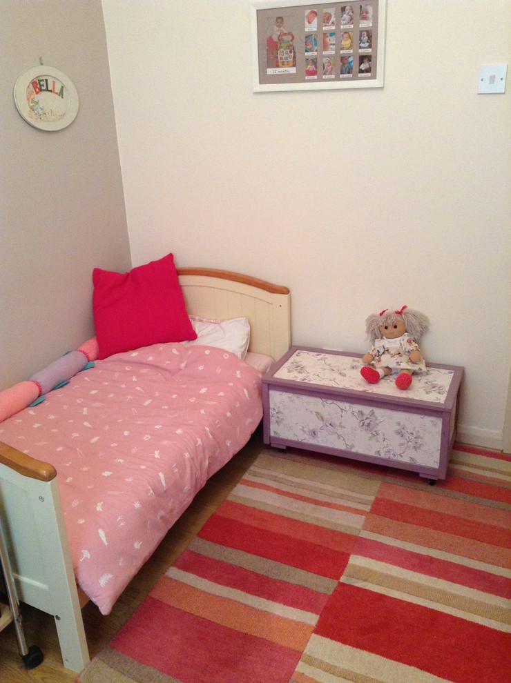 This is an example of a small traditional kids' room for girls in London with beige walls and light hardwood floors.
